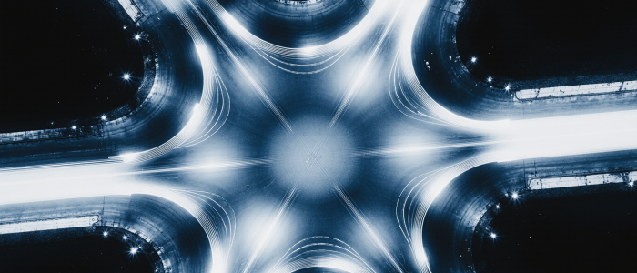 Luftaufnahme eines leuchtenden Verkehrsknotenpunkts bei Nacht, sinnbildlich für Datenströme, Vernetzung und Informationsflüsse.